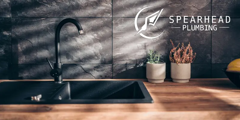 A plumber inspecting a modern kitchen faucet in a family home in Cottleville, MO.